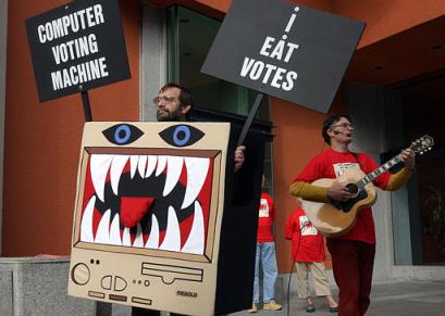 Robert Howe, left, of Placerville, dressed as a vote-eating computer, demonstrates against the touch screen voting systems, while Laramie Crocker, of Berkeley, right, sings against the use of the same  machines outside the Secretary of State's office in Sacramento, Calif., Wednesday, April 21, 2004.  More then a two dozen activisits rallied against the use of electronic voting machines  citing the lack of a paper verification (AP Photo/Rich Pedroncelli)